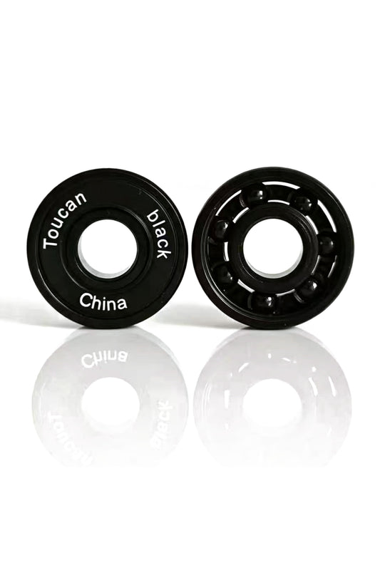 Toucan Black Pro ABEC-9 bearings, one with its rubber seal and one open showing the black ceramic balls